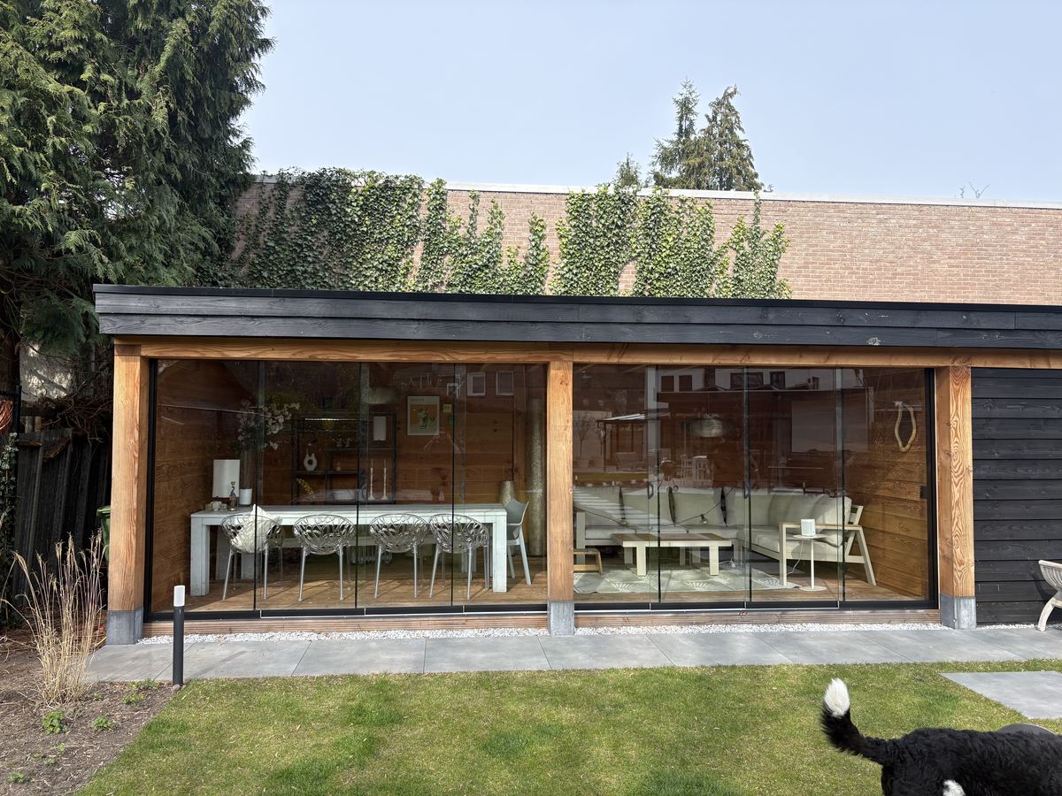 Grote buitenkamer met glazen schuifwanden rondom, douglas constructie met zwarte beplating